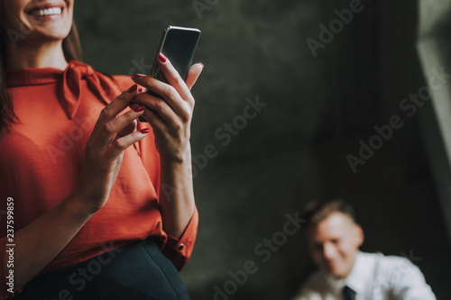 Concept of successful team work. Close up low angle portrait of smiling business lady reading messages on mobile phone