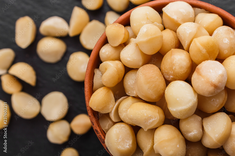 delicious macadamia nuts on a dark stone background delicious macadamia nuts on a dark stone background