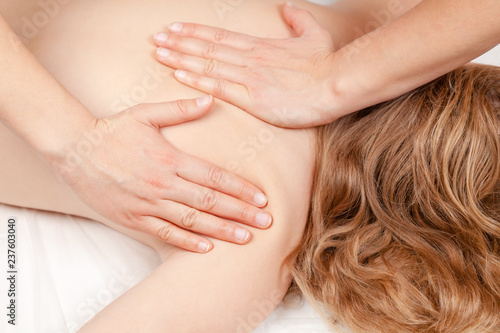 Tween girl receiving osteopathic treatment or medical massage of her shoulder