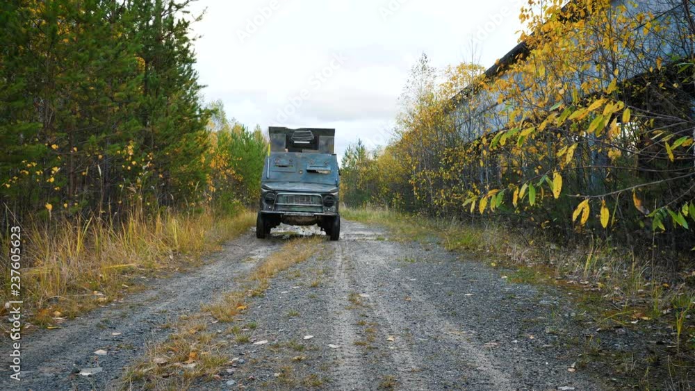 The post-apocalyptic car is moving next to an abandoned industrial building located next to the forest. Autumn time. The post-apocalyptic car is moving next to an abandoned industrial building located next to the forest. Autumn time.