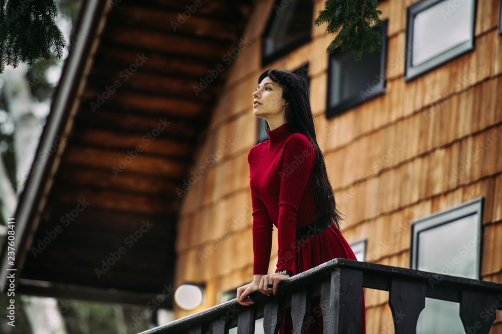 Beautiful woman standing on the porch of wooden house at forest and enjoy the view