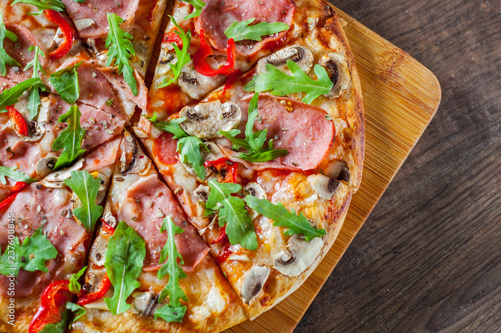 Pizza with Mozzarella cheese, mushrooms, ham, tomato sauce, salami, pepper, Spices and Fresh arugula. Italian pizza on wooden table background Pizza with Mozzarella cheese, mushrooms, ham, tomato sauce, salami, pepper, Spices and Fresh arugula. Italian pizza on wooden table background
