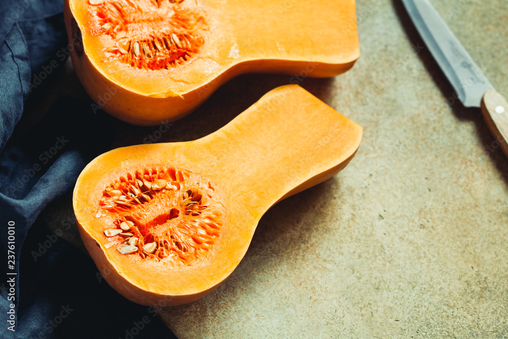 View on raw halves of butternut squash on a kitchen table. Seasonal vegetable food, still life.