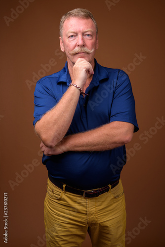 Handsome senior man with mustache against brown background