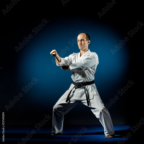 On a blue tatami active athlete trains karate formal exercises