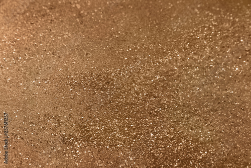Classic shiny bronze/copper glitter background with selective focus - glitter powder - abstract