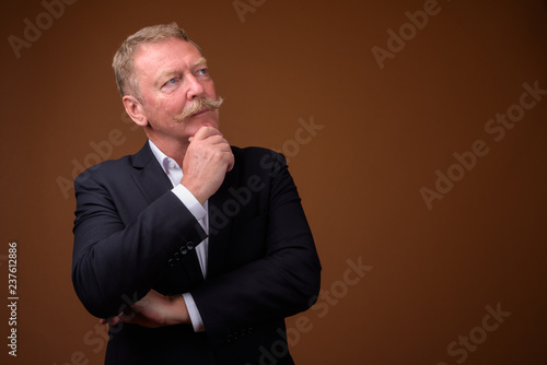 Handsome senior businessman with mustache thinking and looking up