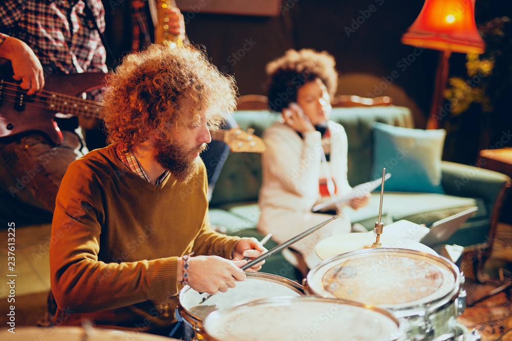 Caucasian drummer playing his instrument while sitting in home studio.