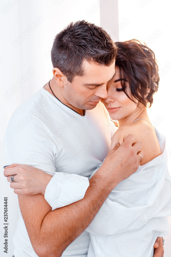 attractive cheerful man and woman sitting near christmas tree hugging. couple cuddling near christmas tree. New year's eve attractive cheerful man and woman sitting near christmas tree hugging. couple cuddling near christmas tree. New year's eve