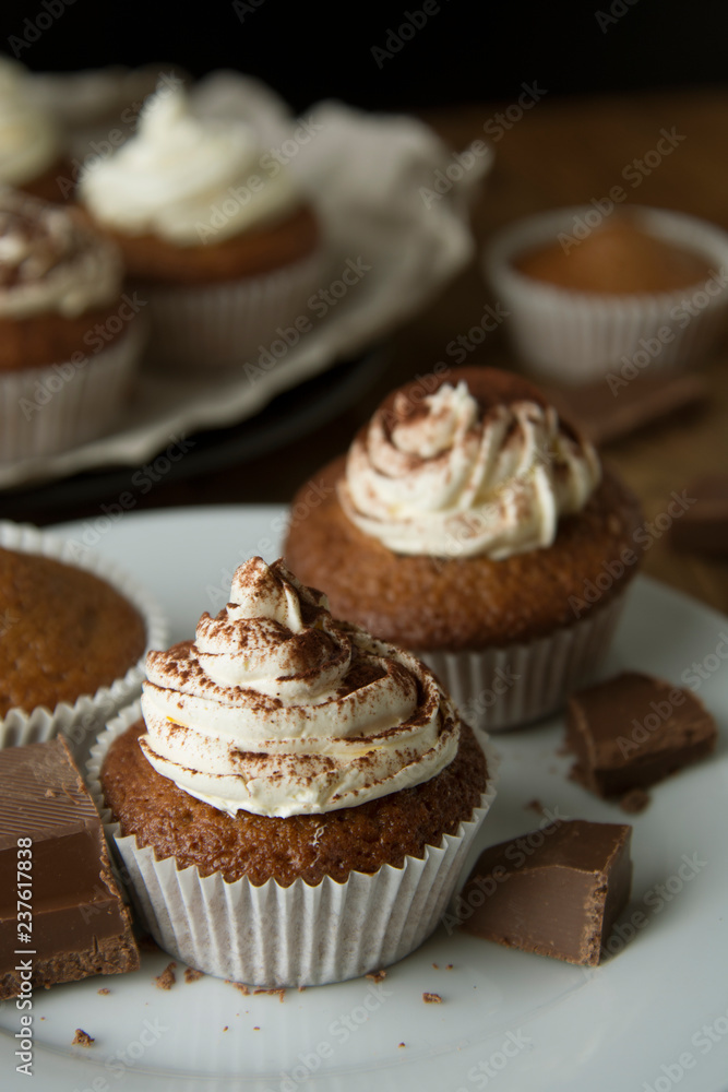 Chocolate cupcakes with whipped cream on rustic wooden table. Homemade dessert. Chocolate cupcakes with whipped cream on rustic wooden table. Homemade dessert.