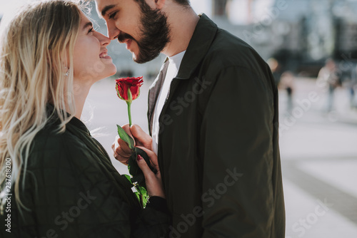 Beautiful young couple holding flower and touching noses on the street #237618200