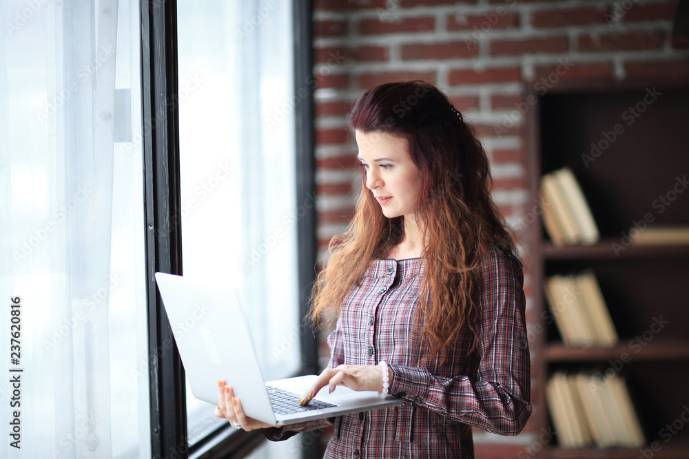 modern business woman is using laptop standing in office. modern business woman is using laptop standing in office.
