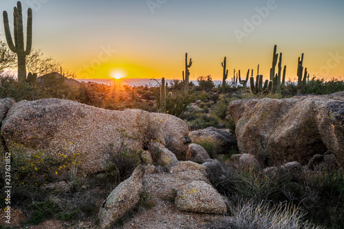 The sun peeks over the mountains, illuminating the desert photo
