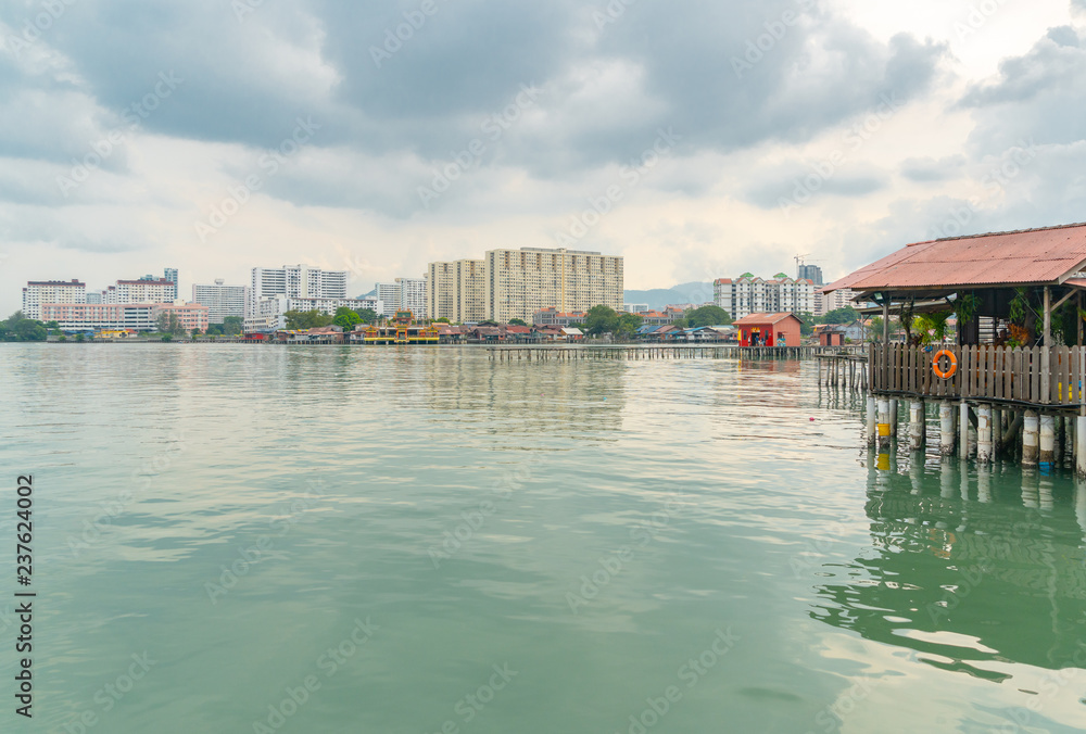A jetty juts out over the tropical bay's glassy waters with new highrise waterfront apartments in the distance contrasting with historic old buildings A jetty juts out over the tropical bay's glassy waters with new highrise waterfront apartments in the distance contrasting with historic old buildings