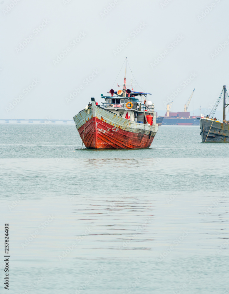 Ancient rusty old fishing vessels made of wood and iron floating on a tropical green bay with a bridge behind Ancient rusty old fishing vessels made of wood and iron floating on a tropical green bay with a bridge behind