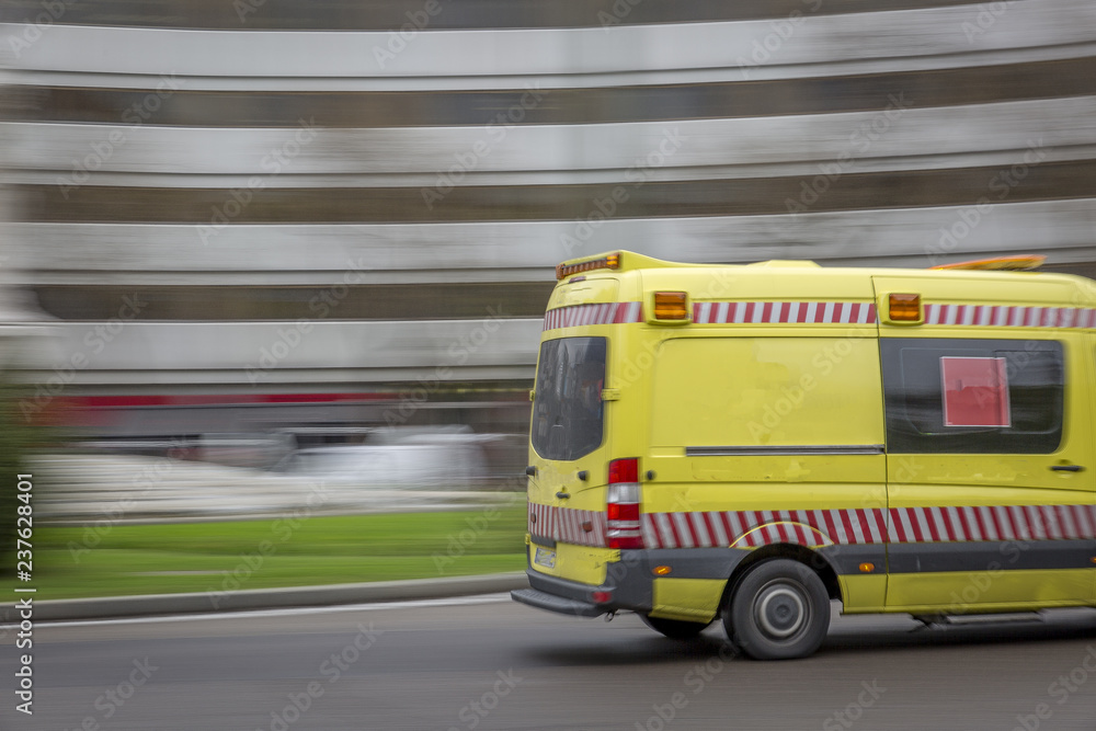 Blurred view of a yellow ambulance transiting a street