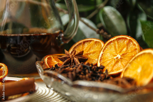 Beautiful composition with anise, cloves, cinnamon stick and powder, tea and dried orange. Wooden table, rustic background and candle light. Close-up.
