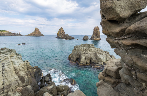 View on the rocky islands in Aci Trezza, Sicily, Italy, with the Islands of the Cyclops in the background. photo