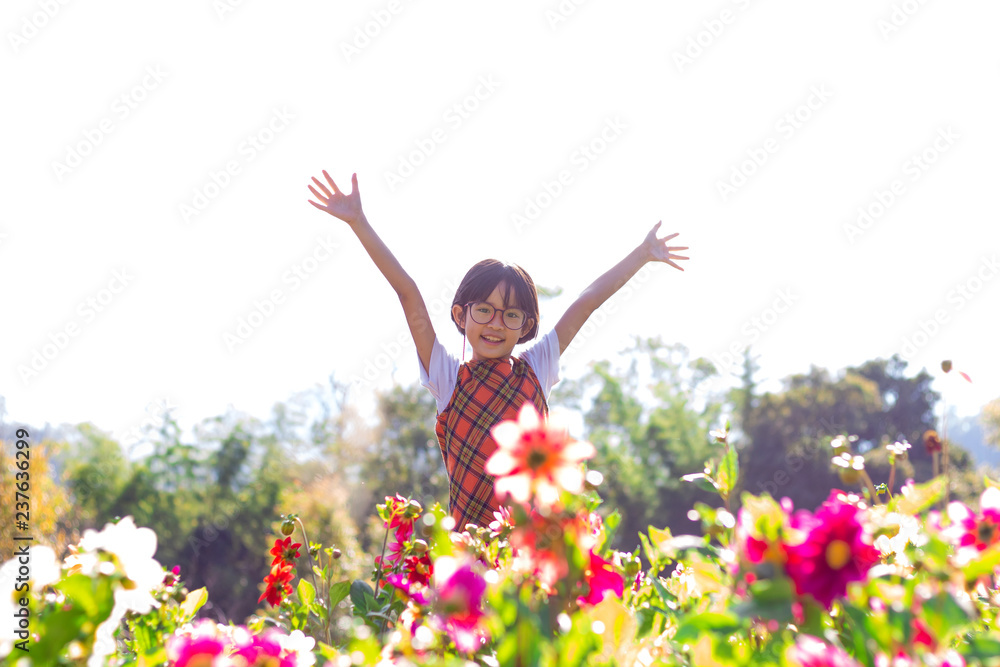 Happy little girl with raised hands in flowers garden Happy little girl with raised hands in flowers garden
