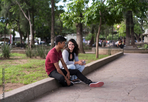 Young woman and man sitting in park