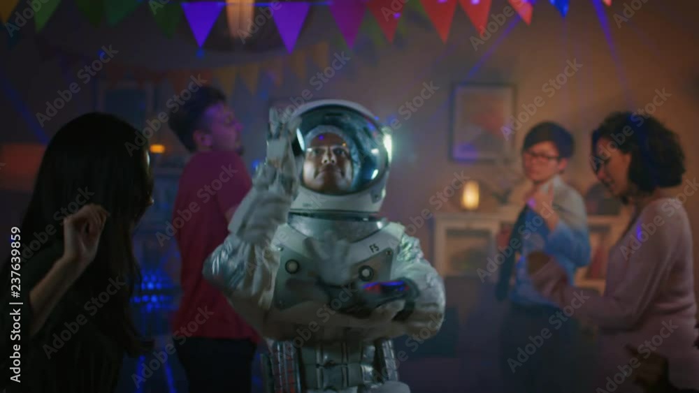 At the College House Costume Party: Fun Guy Wearing Space Suit Dances Off, Doing Groovy Funky Robot Dance Modern Moves. With Him Beautiful Girls and Boys Dancing in Neon Lights. At the College House Costume Party: Fun Guy Wearing Space Suit Dances Off, Doing Groovy Funky Robot Dance Modern Moves. With Him Beautiful Girls and Boys Dancing in Neon Lights.
