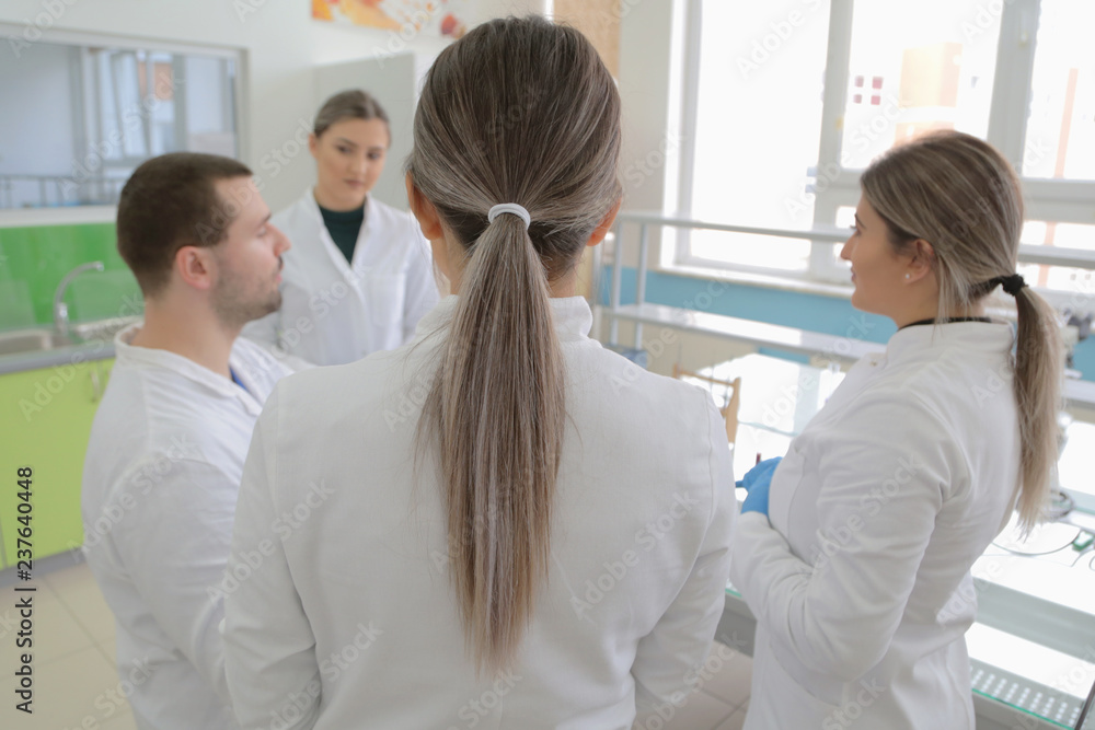 Group of young Laboratory scientists working at lab with test tubes and microscope, test or research in clinical laboratory.Science, chemistry, biology, medicine and people concept.