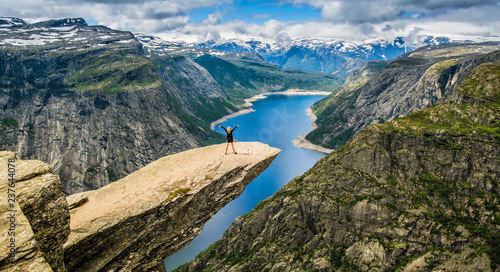 Amazing nature view with Trolltunga and a girl standing  on it. Location: Scandinavian Mountains, Norway, Stavanger. Artistic picture. Beauty world. The feeling of complete freedom photo