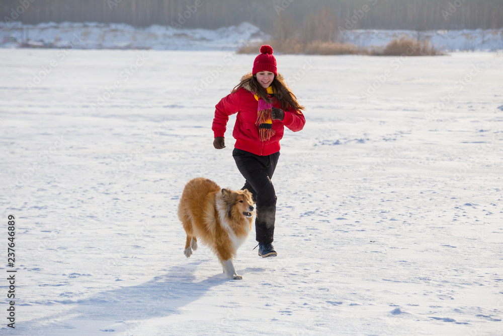 Girl running with collie dog at winter landscape