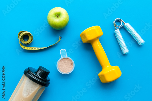 sport nutrition set with protein powder for cocktail and scoop on blue background top view space for text