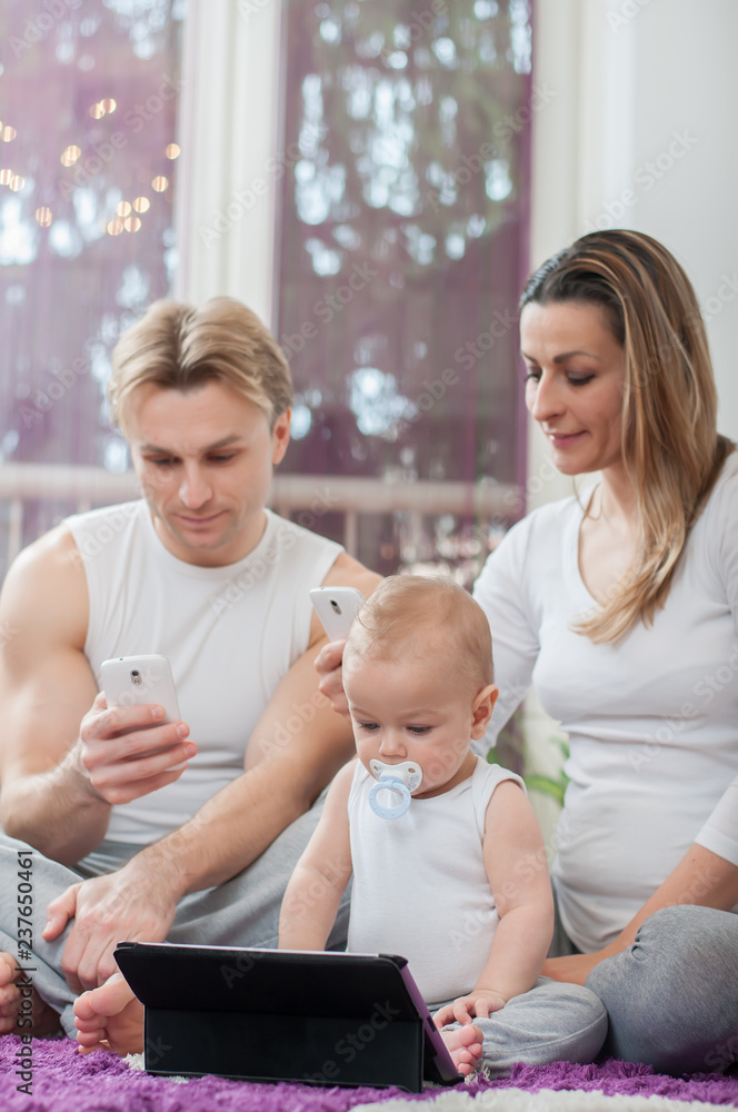 Happy parents sitting on the floor and playing with their baby boy. Computer era. Happy parents sitting on the floor and playing with their baby boy. Computer era.