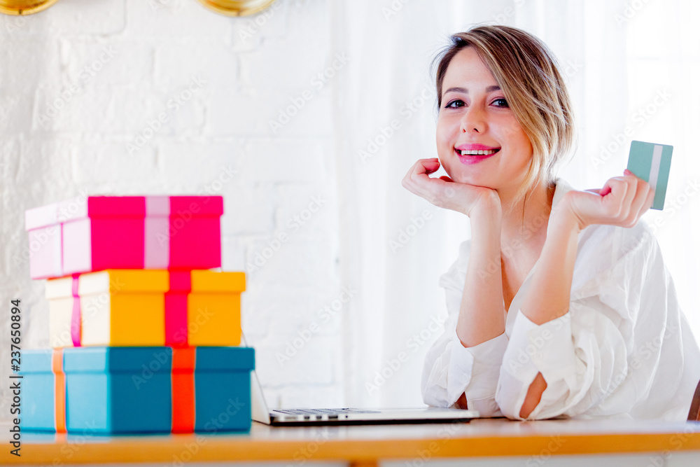 Young girl with holiday gifts and laptop computer holding a credit card. Business, education, shopping and other concept Young girl with holiday gifts and laptop computer holding a credit card. Business, education, shopping and other concept