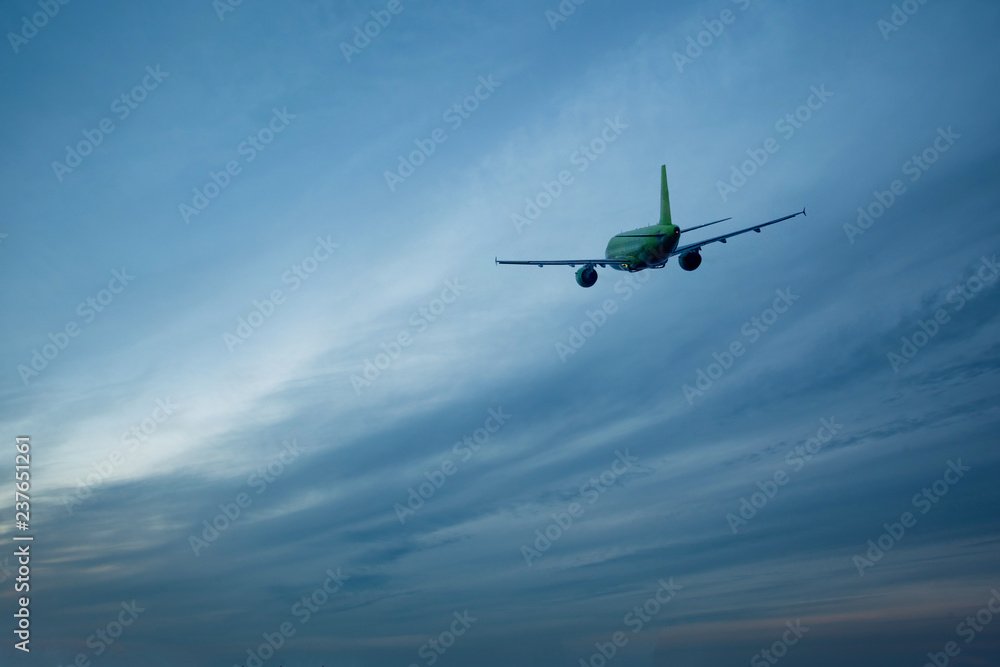 takeoff of a green passenger airplane against a blue sunset sky