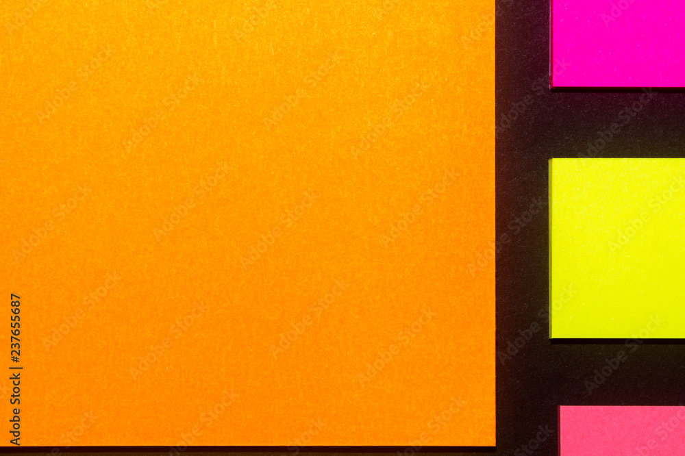 Fototapeta premium Yellow, orange and rose hue colorful office stickers on black paper. Office noteparer as reminder. Isolated on black paper.