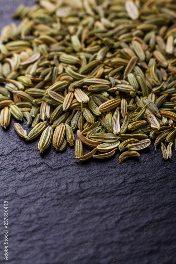 Essential oil of fennel seeds on a dark stone background