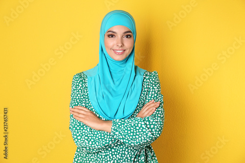 Portrait of young Muslim woman in hijab against color background