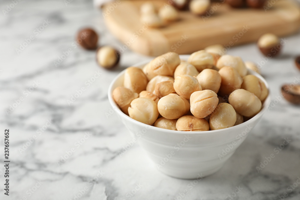Bowl with shelled organic Macadamia nuts and space for text on marble table Bowl with shelled organic Macadamia nuts and space for text on marble table