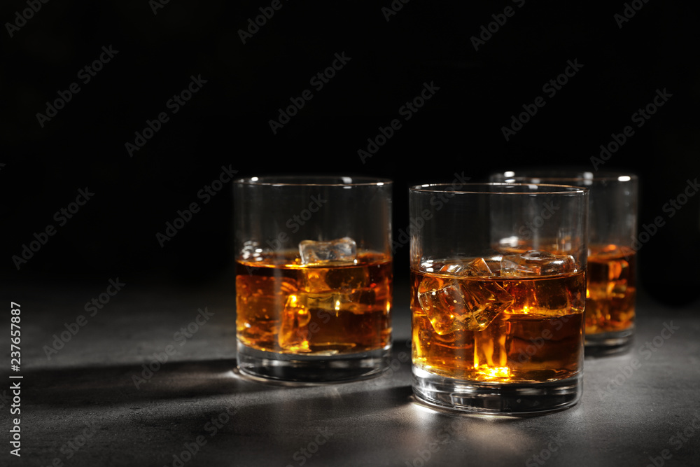 Golden whiskey in glasses with ice cubes on table. Space for text Golden whiskey in glasses with ice cubes on table. Space for text