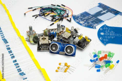 Various sensors and components for creating electrical circuits, devices or robots. Buttons, switches, motion sensor, digital display, wires, diodes, resistors on a white background.