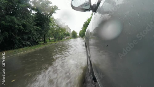 Natural disaster, flooding after heavy rains. The car drives on flooded road, car traffic safety issues