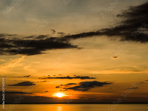 Sunset across the ocean with orange sky and island silhouettes on the horizon
