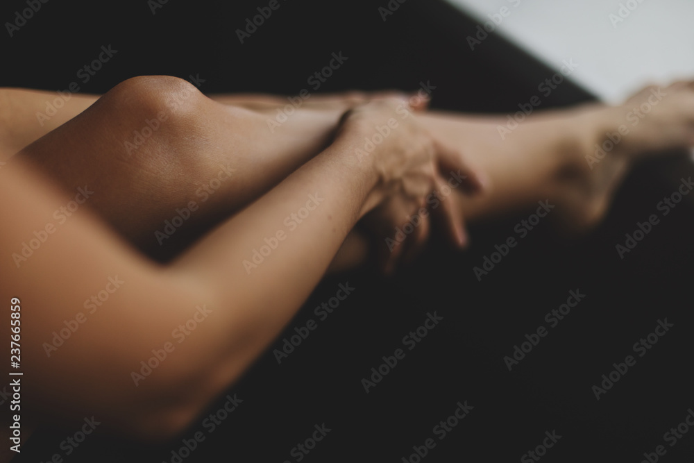 Fototapeta premium Young woman smearing cream on her leg. Epilation concept. Sexy