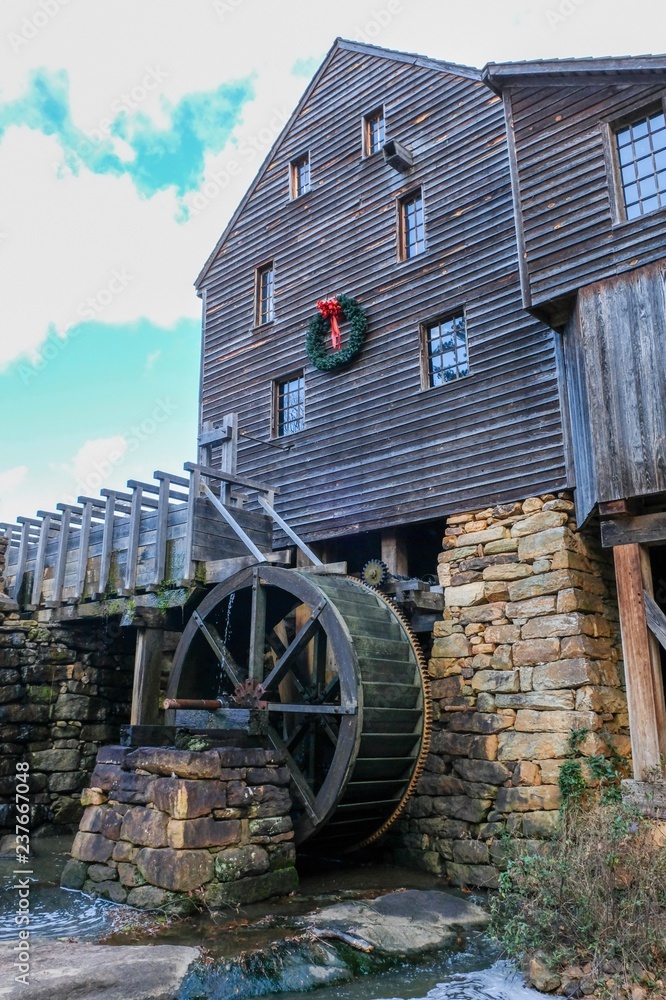 Obraz premium Old watermill decorated with a holiday wreath for Christmas at Historic Yates Mill County Park in Raleigh North Carolina