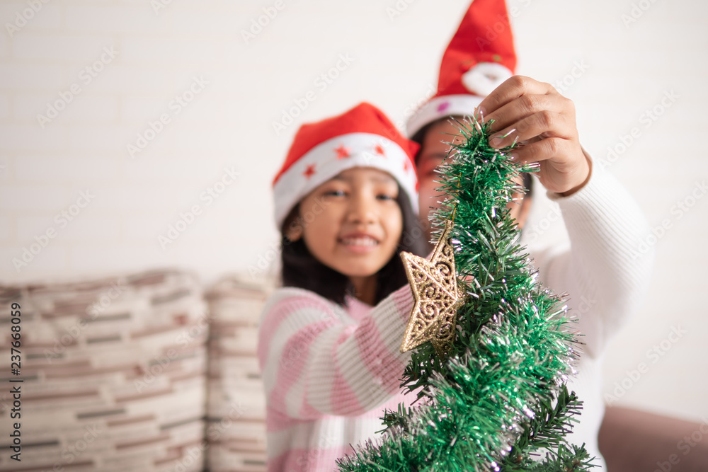 Asian little girl with mother decorating christmas tree for party with happiness