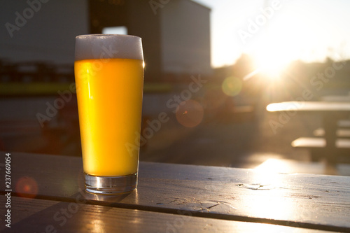 Full glass of beer on picnic table at golden hour