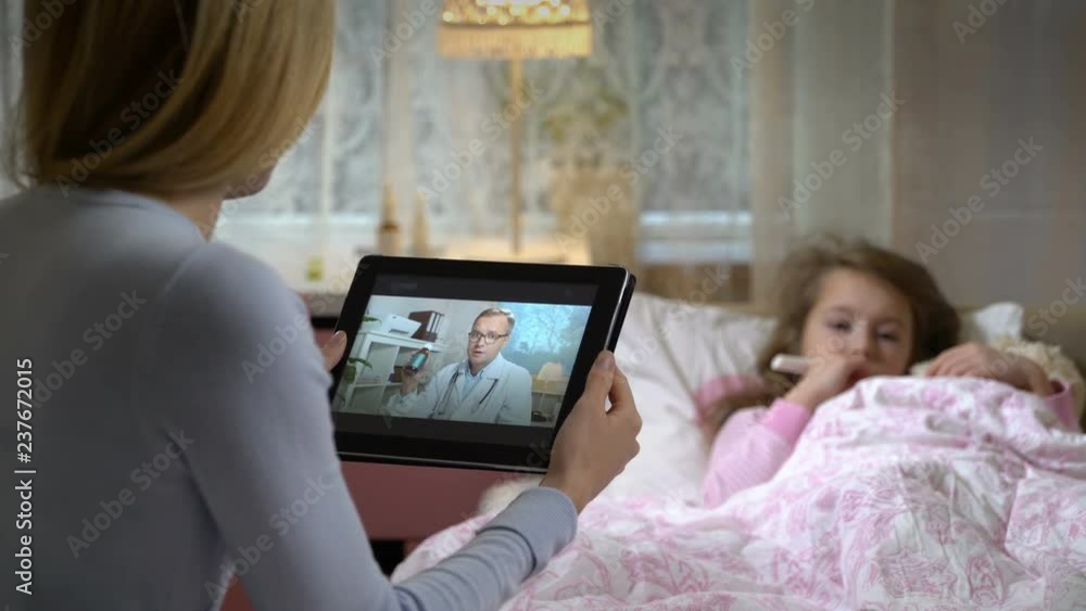 Medicine online. Home quarantine coronavirus. Mom with a little sick daughter gets a doctor's advice using video chat at home. Male doctor prescribing her medicine. Medicine online. Home quarantine coronavirus. Mom with a little sick daughter gets a doctor's advice using video chat at home. Male doctor prescribing her medicine.