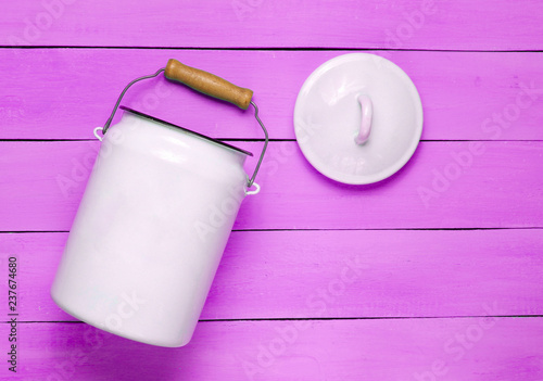 Enameled milk can on violet wooden background. Top View. photo