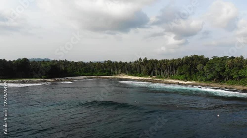 Drone elevating above waves and surfers in a beach cove called Wong Tong. Most consistant reef break in the area on the remote island of Simeulue, off the coast of North Sumatra in Indonesia. photo