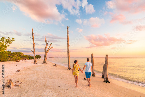 Billede på lærred Couple walking on beach at sunset romantic travel getaway, idyllic Florida destination, Lovers key beach state park in the gulf of Mexico
