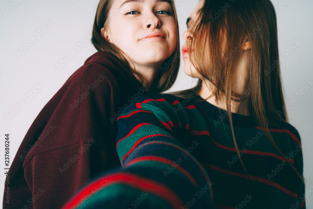 Two sisters twins beautiful girls in casual taking selfie on fro Two sisters twins beautiful girls in casual taking selfie on fro