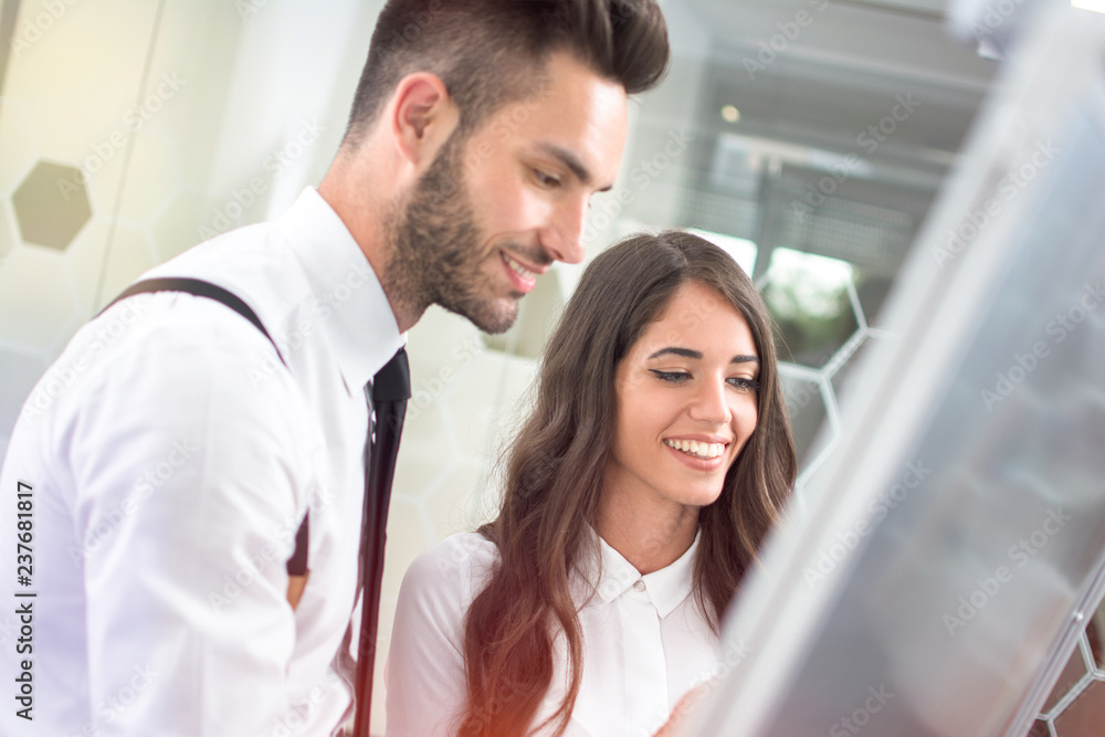 Portrait of attractive business woman and handsome businessman working together in front of flipchart in the office Portrait of attractive business woman and handsome businessman working together in front of flipchart in the office